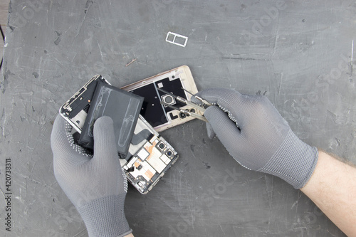 men's hands in special gloves repair a smartphone. the concept of computer hardware, mobile phone, electronic, repairing, upgrade and technology.