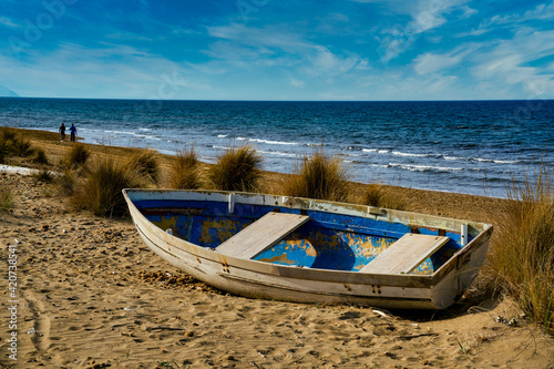 Small boat abandoned on the dunes of Donoratico beach Tuscany Italy