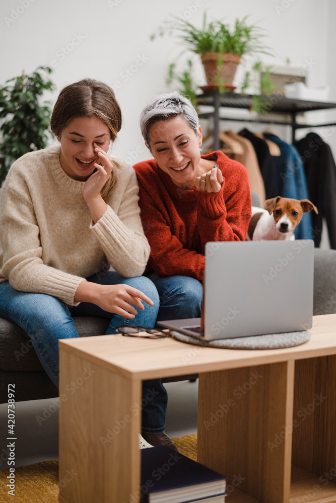 Laughing women with laptop and dog resting at home Laughing women with laptop and dog resting at home