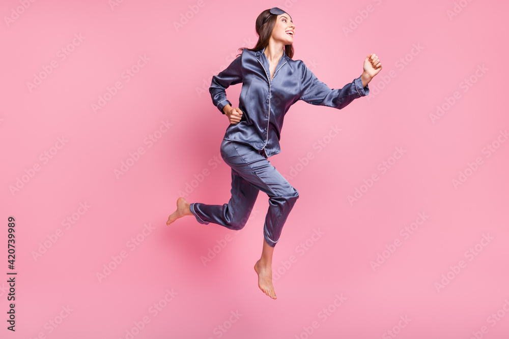 Full length body size side profile photo of girl wearing nightwear jumping running on pajama party isolated on pastel pink color background