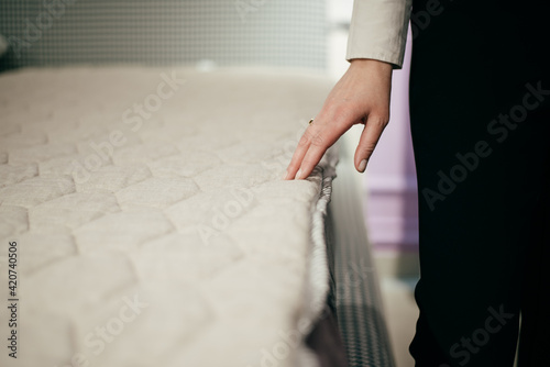 Woman s hand pressing on white mattress. Empty place for text