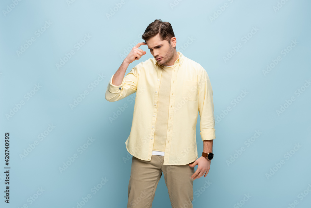 pensive young man looking down while thinking on blue pensive young man looking down while thinking on blue