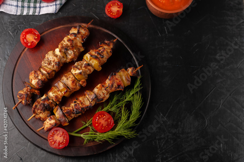 Chicken skewers with apples and vegetables on a black background