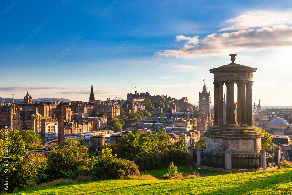 Naklejka premium Edinburgh cityscape as viewed from the Calton Hill with the Dugald Stewart Monument in foreground in the evening sun