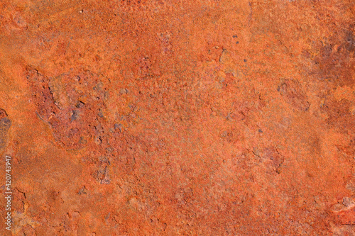 The texture of an old metal surface coated with a layered orange rust.