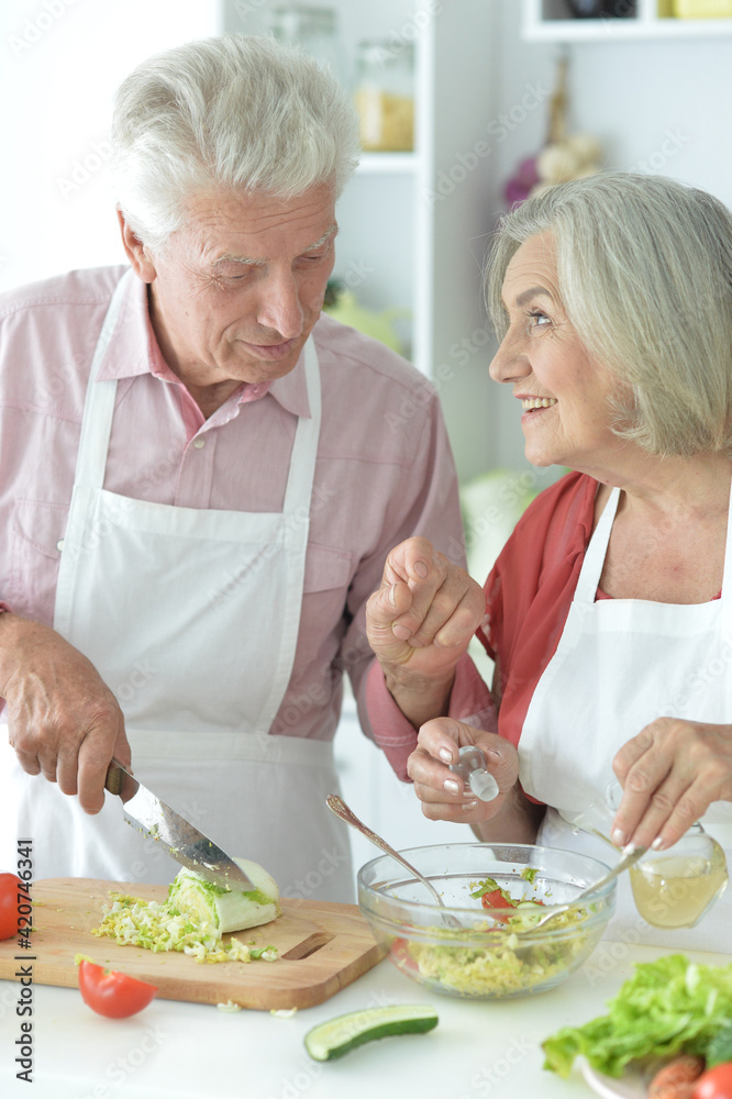 Senior couple making salad together at kitchen Senior couple making salad together at kitchen