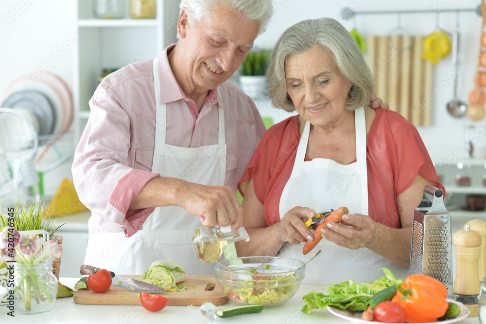 Senior couple making salad together at kitchen