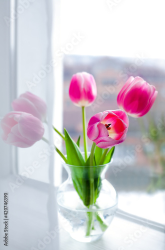 Pink tulips bouquet in glass vase on the window. Springtime. Close-up.