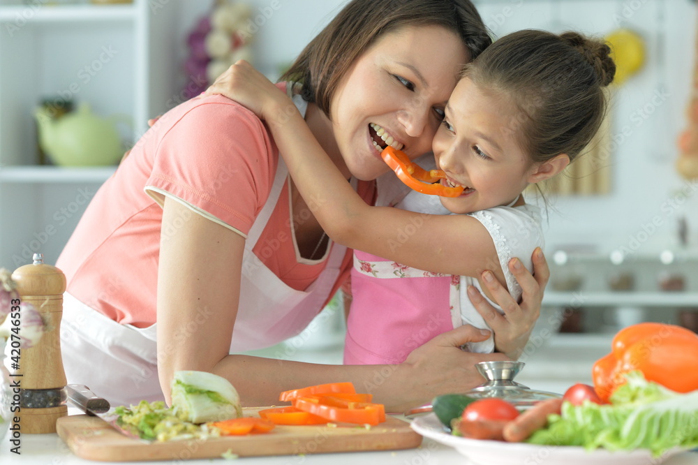 Cute little girl with her mother cooking together at kitchen table Cute little girl with her mother cooking together at kitchen table