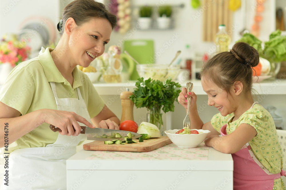 Cute little girl with her mother cooking together at kitchen table Cute little girl with her mother cooking together at kitchen table
