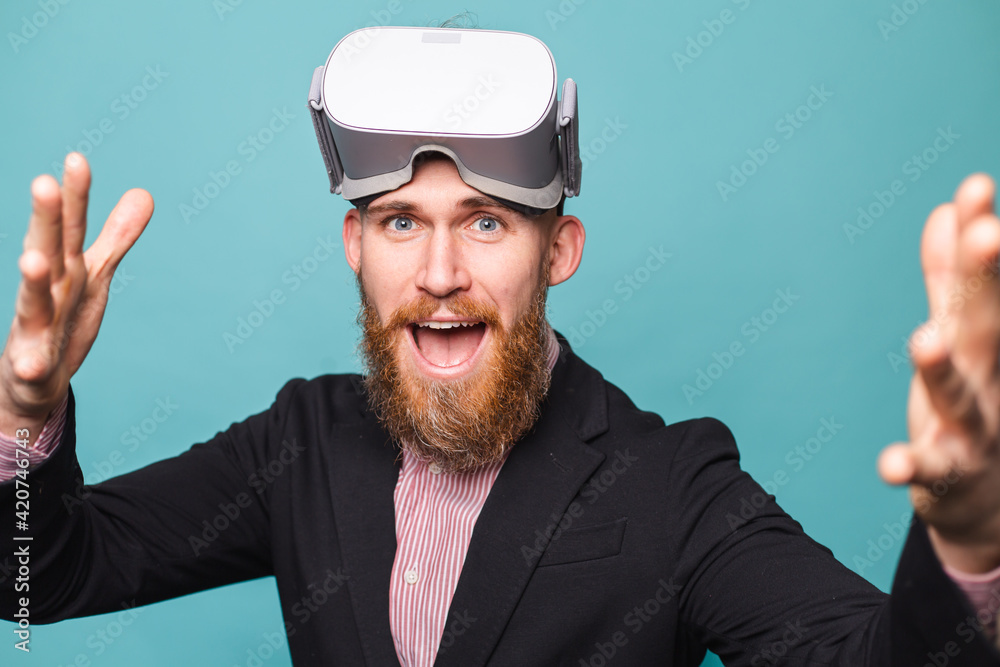 Bearded european businessman in dark suit isolated on turquoise background wearing vr glasses on head with excited happy face Bearded european businessman in dark suit isolated on turquoise background wearing vr glasses on head with excited happy face