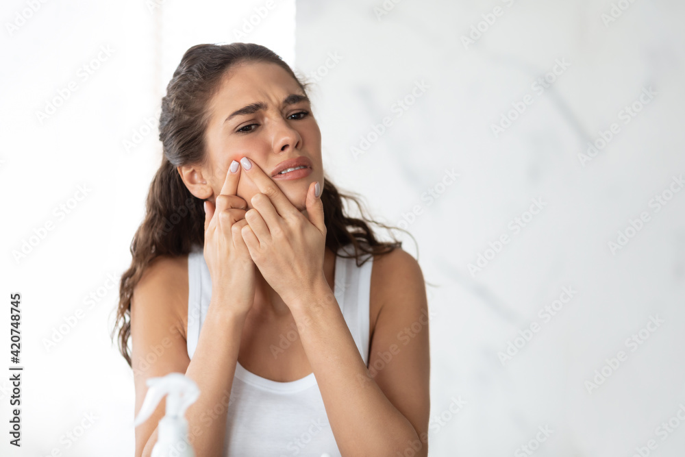 Frustrated Lady With Acne Problem Squeezing Pimple On Cheek Indoor Frustrated Lady With Acne Problem Squeezing Pimple On Cheek Indoor