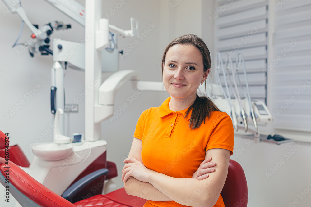 portrait young friendly female dentist smiling and looking at camera in a modern dental office. attractive woman specialist doctor sitting a chair with crossed arms on a white equipment background
portrait young friendly female dentist smiling and looking at camera in a modern dental office. attractive woman specialist doctor sitting a chair with crossed arms on a white equipment background