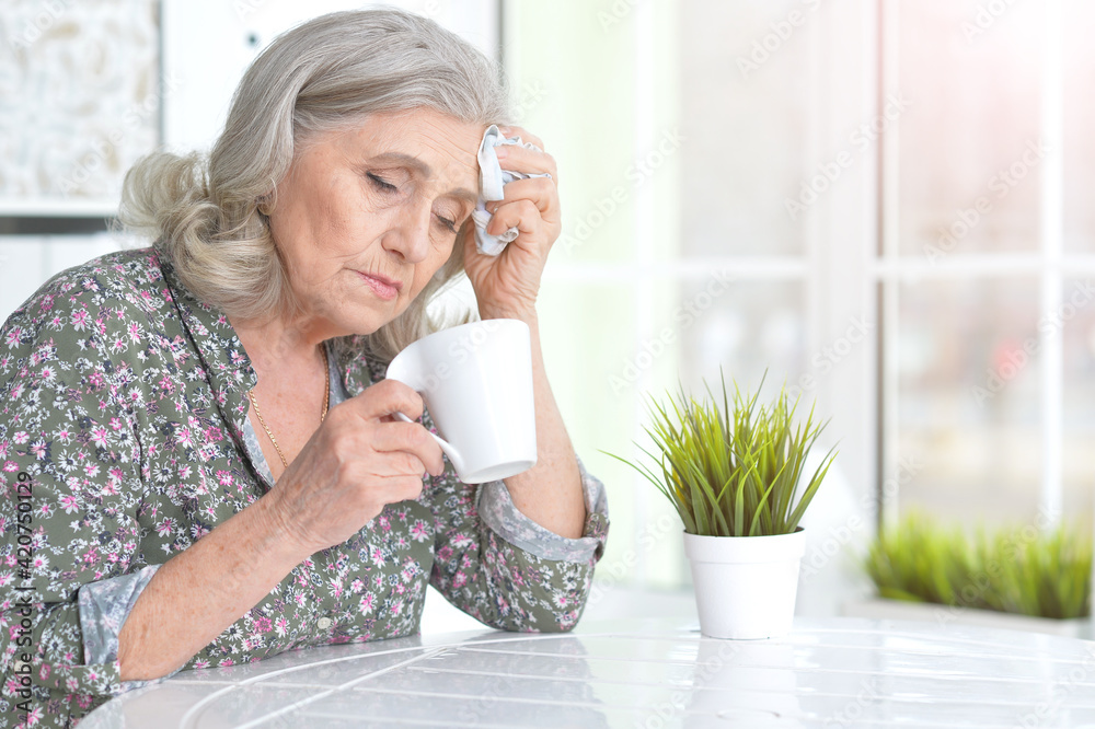 Sick senior woman sitting at table