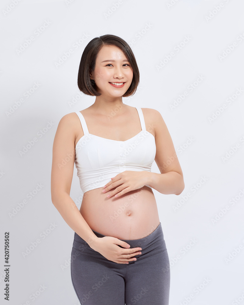 A beautiful Asian woman standing touching her belly. Pregnancy and expectation concept A beautiful Asian woman standing touching her belly. Pregnancy and expectation concept