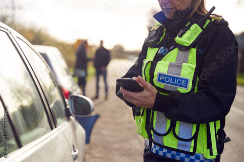 Female Traffic Police Officer Recording Details Of Road Traffic Accident On Mobile Phone photo