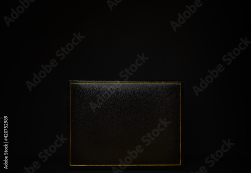 Black gift box with golden frame on black background, black on black photo