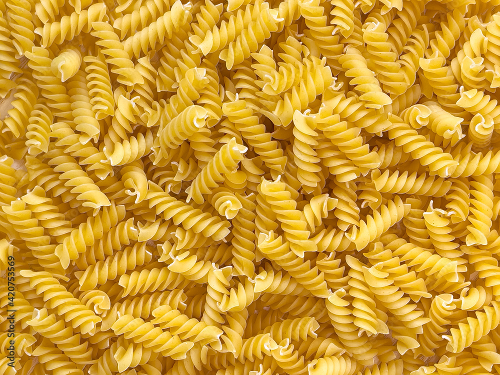 Food background or texture raw dry Italian pasta in shape of spiral. Closeup, macro, top view. Uncooked macaroni Food background or texture raw dry Italian pasta in shape of spiral. Closeup, macro, top view. Uncooked macaroni