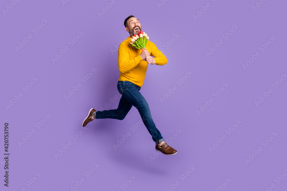 Profile photo of dreamy man jump run hold bunch flowers wear yellow sweater jeans shoes isolated violet background