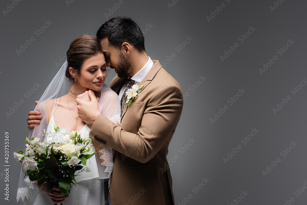 elegant arabian man embracing woman in wedding dress on grey elegant arabian man embracing woman in wedding dress on grey