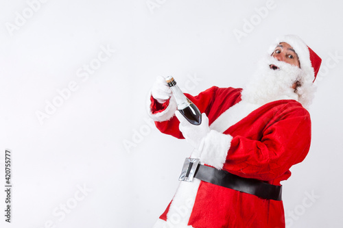 Babbo natale apre felice una bottiglia di spumante , isolato su sfondo bianco photo