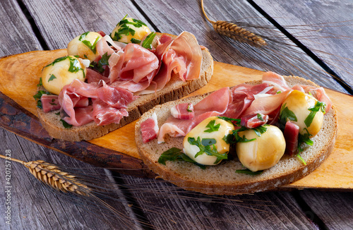 snack appetizer with wholemeal bread, raw ham and smoked provola