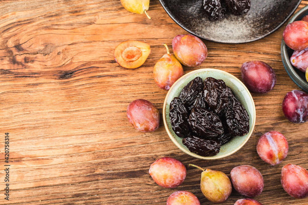 Fresh  prune and dried  prune on wooden board background