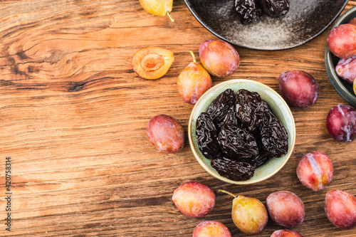 Fresh prune and dried prune on wooden board background