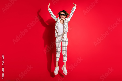 Full size photo of young attractive girl excited happy positive smile have fun enjoy jump rejoice isolated over red color background