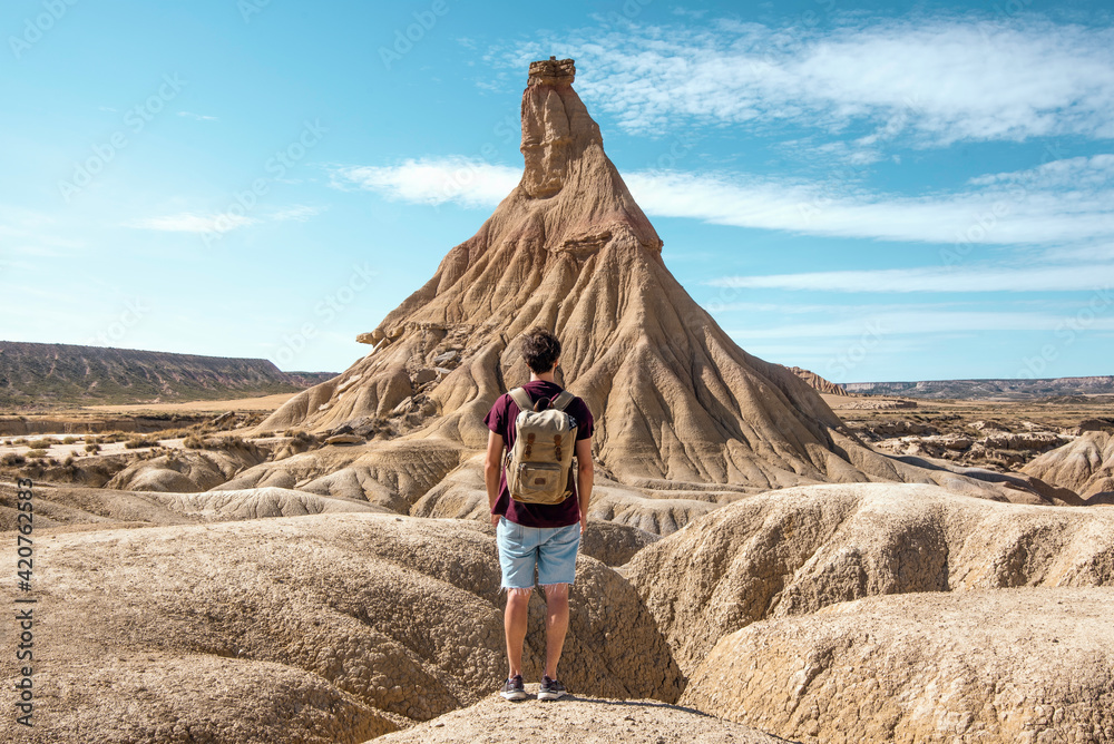 young boy with backpack and short jeans traveling in the desert landscape of Bardenas Reales, Navarra