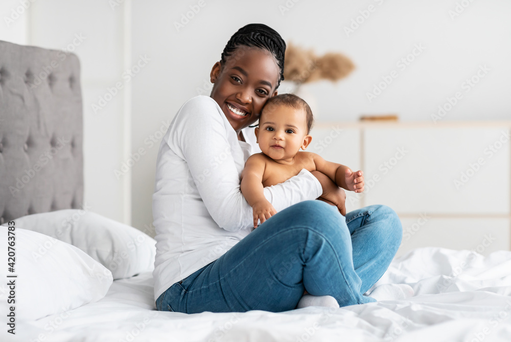 Black mom sitting on bed with her cute baby Black mom sitting on bed with her cute baby