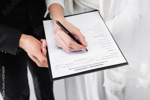 Cropped view of couple signing marriage contract isolated on grey