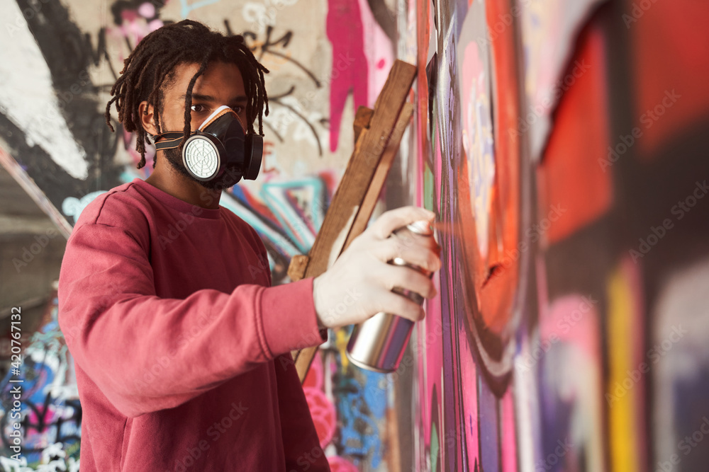 Naklejka premium Street artist painting colored graffiti