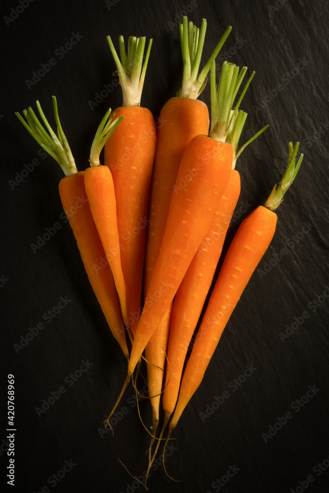 Fresh organic carrots peeled for a healthy diet, on a black background