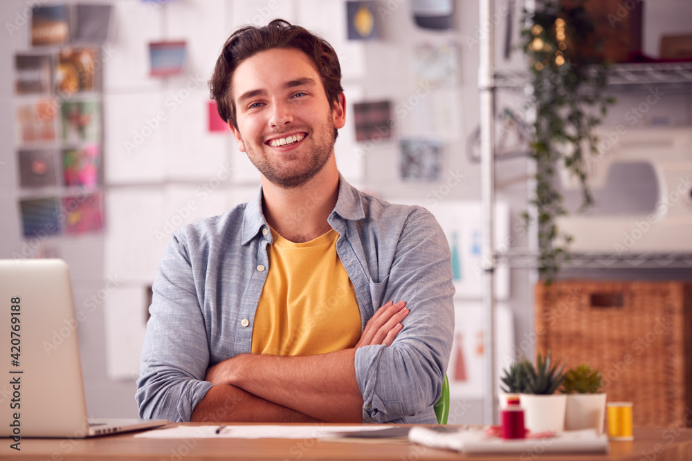 Portrait Of Smiling Male Student Or Business Owner Working In Fashion Using Laptop In Studio Portrait Of Smiling Male Student Or Business Owner Working In Fashion Using Laptop In Studio