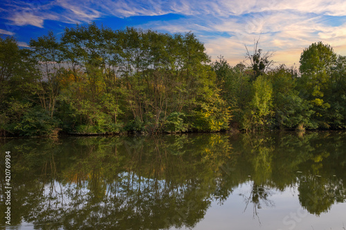 Landscape by the water. Stara Dyje river near Genoa castle in Czech republic. Trees are reflected in the river. Calm water. Colorful autumn. Beautiful clouds in the sky.