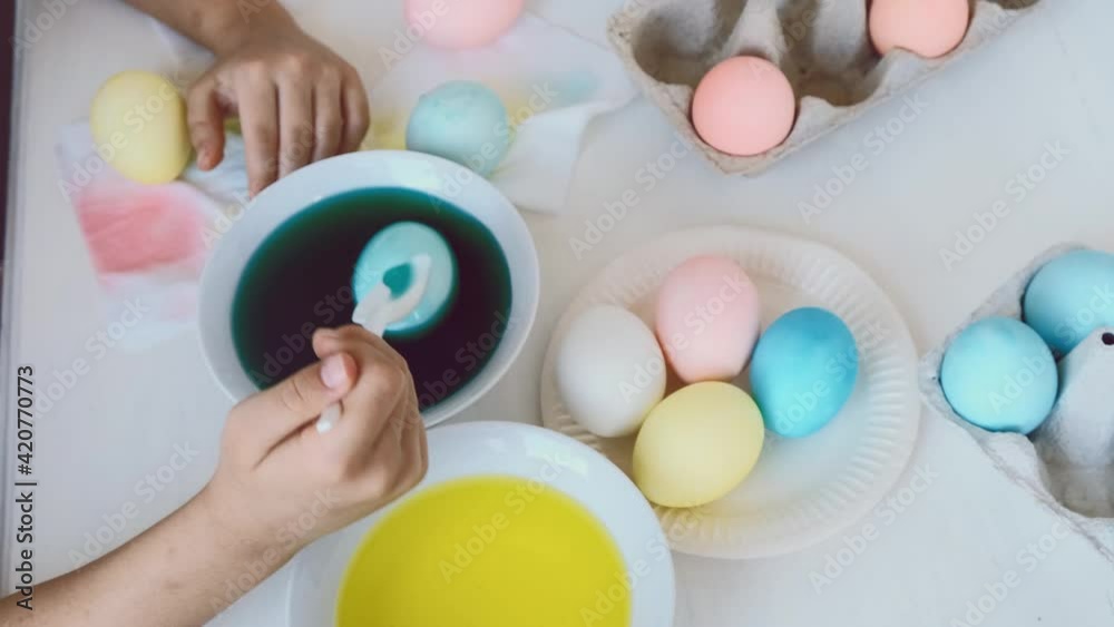 Close up of girl hands coloring easter submerge eggs in liquid green dye. Close up of girl hands coloring easter submerge eggs in liquid green dye.