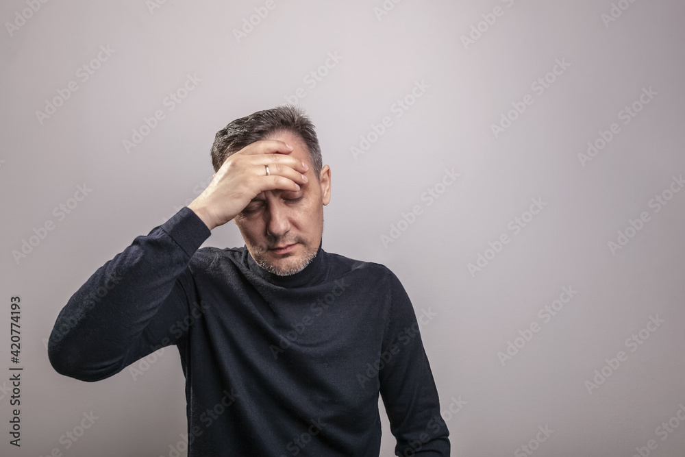 A white middle aged man of European appearance with gray in his hair and a slightly unshaven face in a black turtleneck holds his hand to his forehead in despair A white middle aged man of European appearance with gray in his hair and a slightly unshaven face in a black turtleneck holds his hand to his forehead in despair
