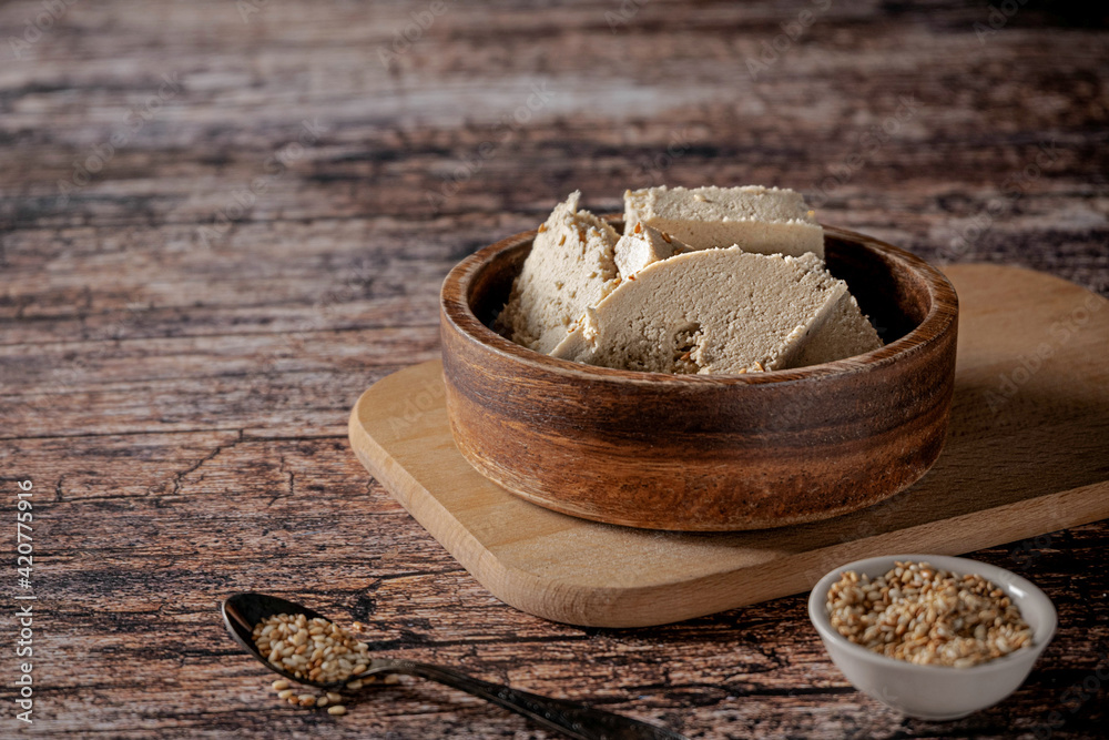 Pieces of tahini halva in a bowl on vintage wooden background, with sesame seeds as its main ingredient Pieces of tahini halva in a bowl on vintage wooden background, with sesame seeds as its main ingredient