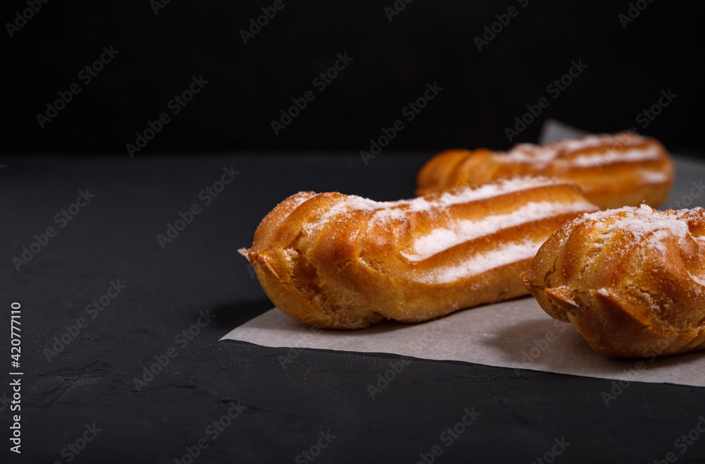 Eclairs with cream on a dark background