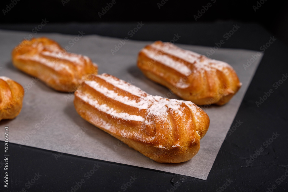 Eclairs with cream on a dark background