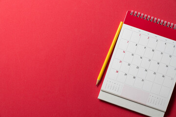 close up of calendar and yellow pencil on the red table background, planning for business meeting or travel planning concept