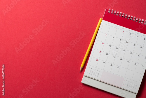 close up of calendar and yellow pencil on the red table background, planning for business meeting or travel planning concept photo