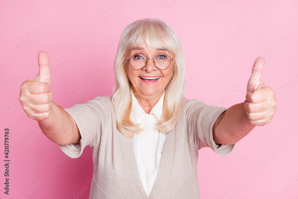 Photo portrait of elderly lady giving two thumbs up isolated on pastel pink colored background Photo portrait of elderly lady giving two thumbs up isolated on pastel pink colored background