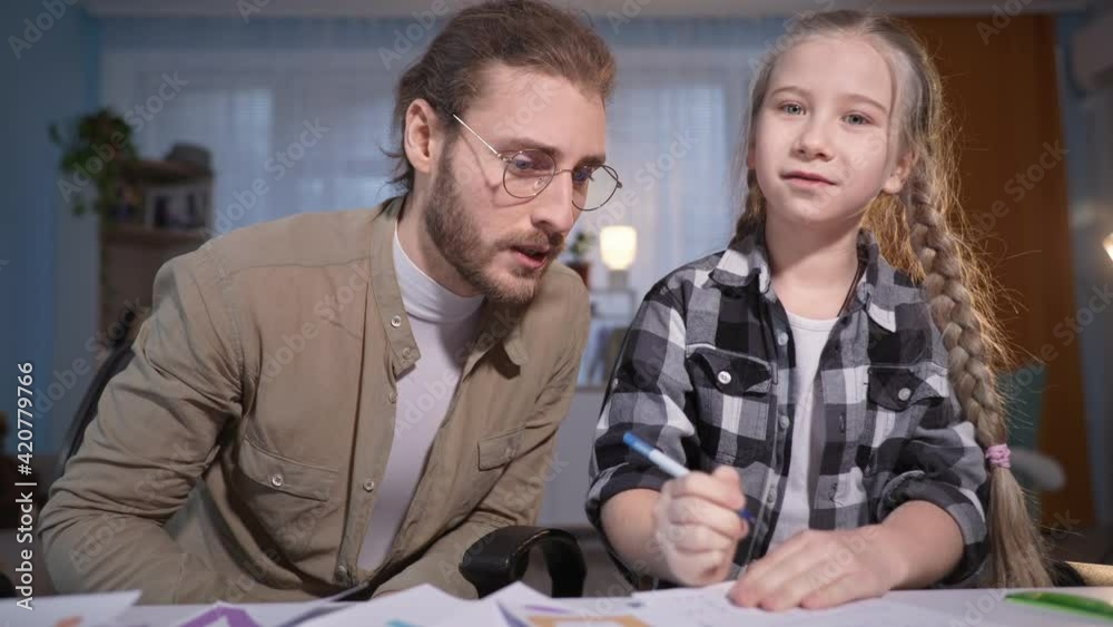 portrait of family during an online lesson, girl writes in a notebook and then gives five to her father, parent and daughter dance cheerfully for camera portrait of family during an online lesson, girl writes in a notebook and then gives five to her father, parent and daughter dance cheerfully for camera