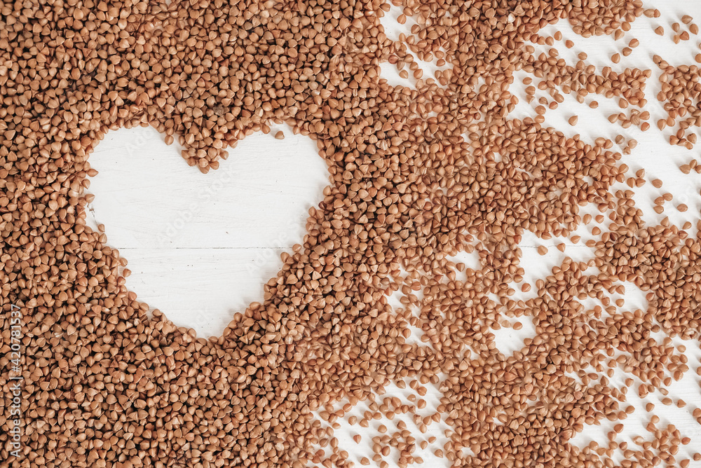 Buckwheat as a heart background texture on a white background. Top view. Copy, empty space for text Buckwheat as a heart background texture on a white background. Top view. Copy, empty space for text