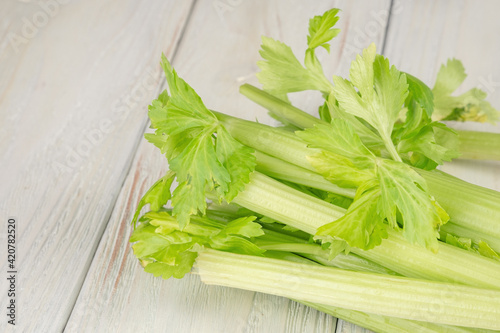 Bunch of fresh celery stalk with leaves on a wooden background