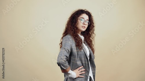 Wallpaper Mural The arrogant young woman, confident with her hands in the middle, in profile, looks into the room. Cretaceous in gray jacket and white shirt, with glasses posing isolated on a beige background in the Torontodigital.ca