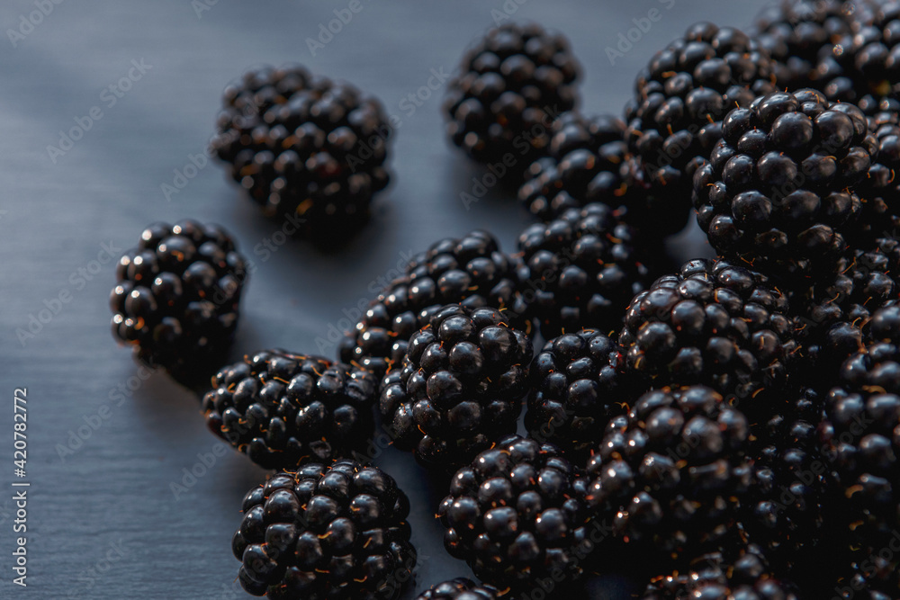 Close-up view on juicy and tasty blackberry fruits laying on grey table. Selective focus. Close-up view on juicy and tasty blackberry fruits laying on grey table. Selective focus.
