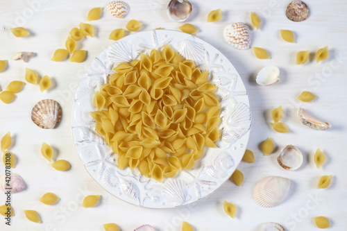 Raw shell pasta in sea style decorated plate on white wooden background